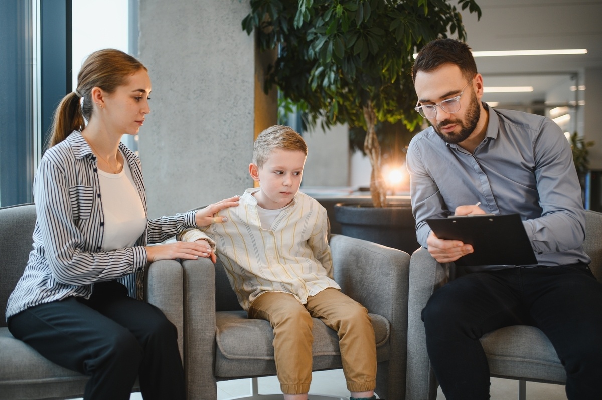 Special needs care coordinator reviewing a care plan with a mother and child during a coordination meeting