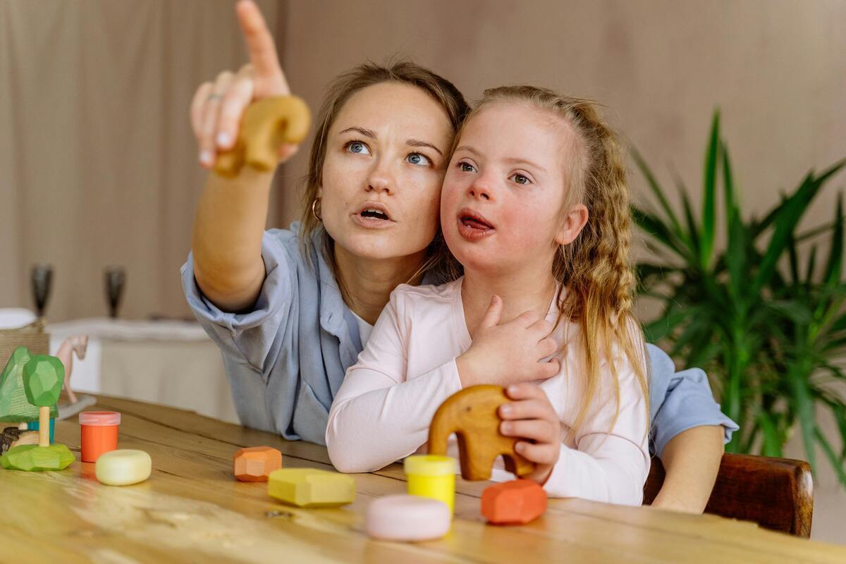Caregiver guiding a child with Down syndrome through a structured play activity as part of children with special needs care in Queens NY