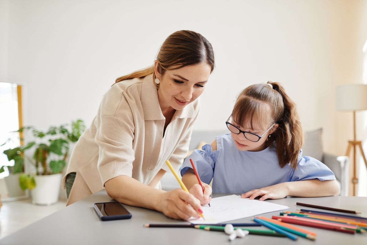 Caregiver helping a child with a drawing activity during OPWDD Services in Sheepshead Bay